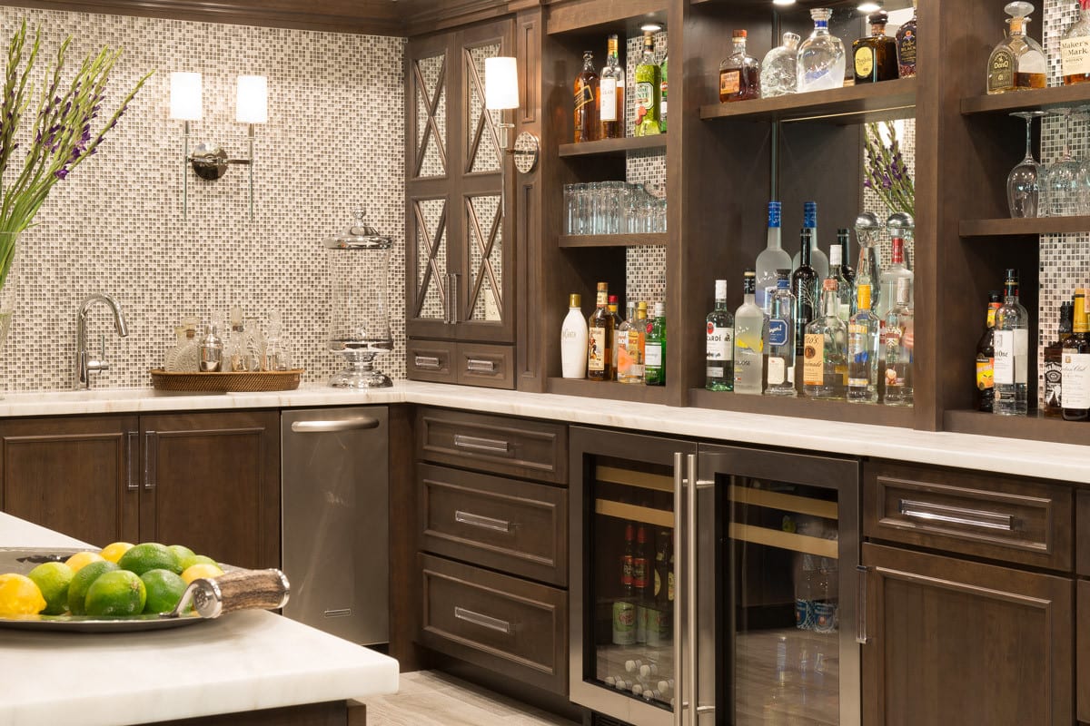 a spacious entertainment bar with wooden cabinetry and multicolored square backsplash