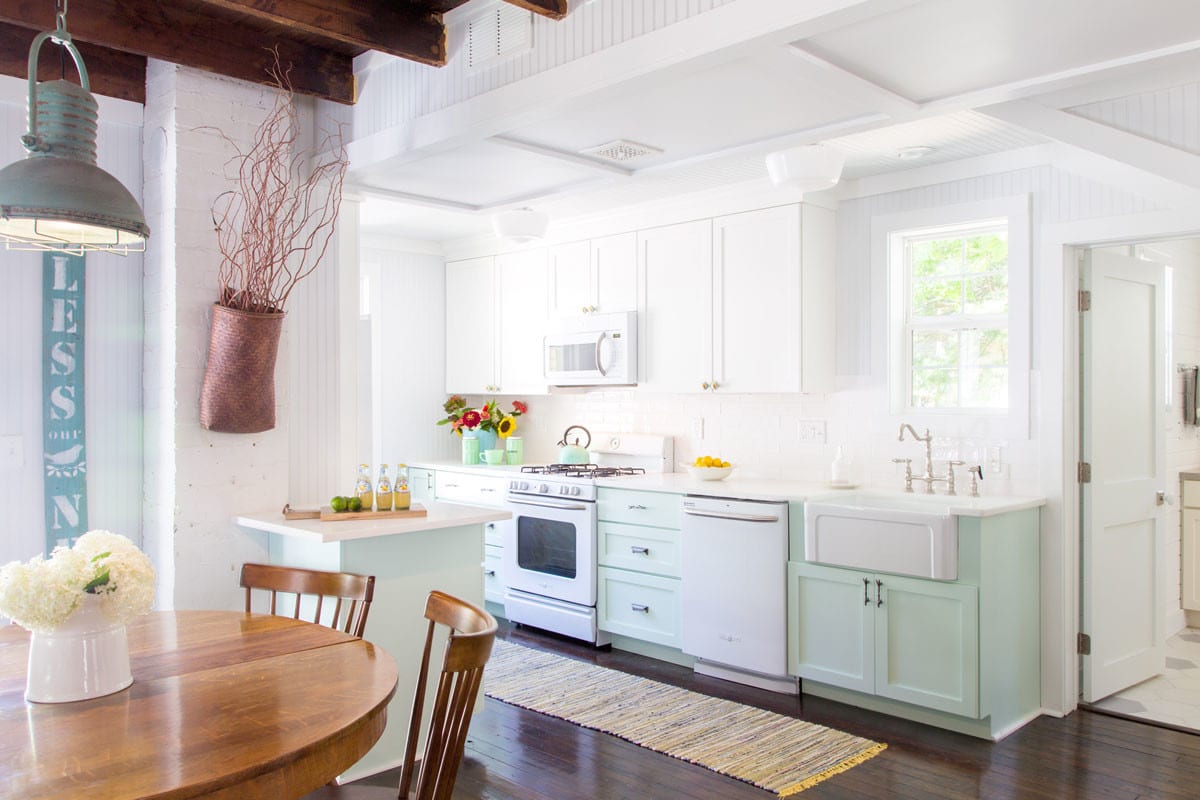 a cottage style kitchen with mint green and white cabinetry