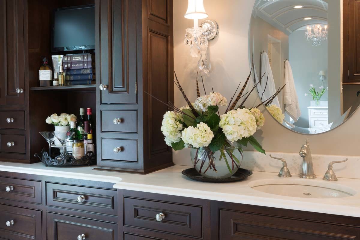 a master bath with dark cabinetry and white countertops