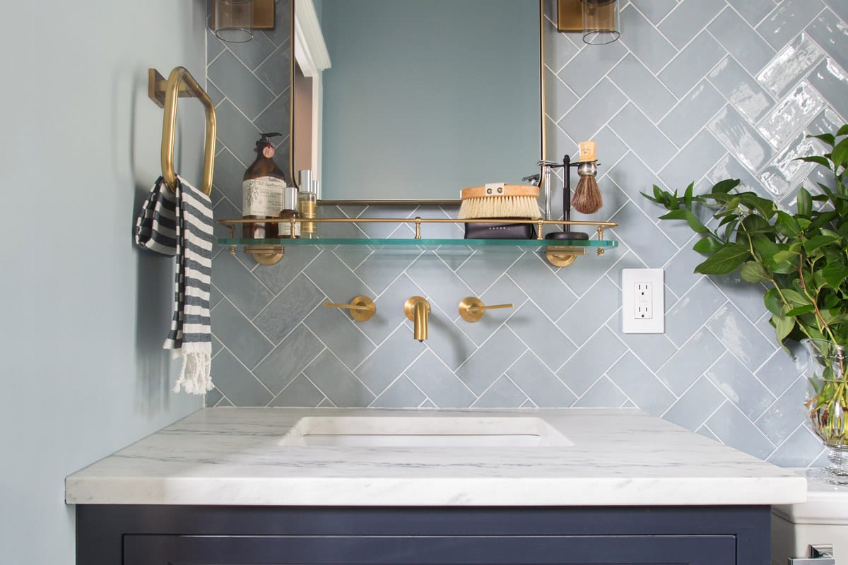 cute classy casual light powder blue herringbone pattern bathroom renovation navy cabinet granite countertop gold accents.
