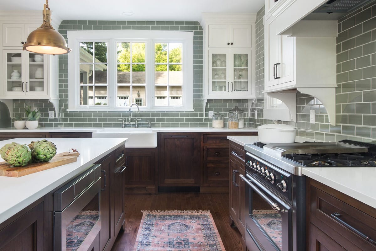 spacious kitchen with moss green subway tile and dark brown wooden cabinetry