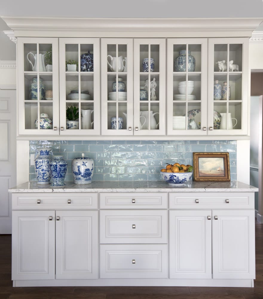 a built in wet bar with a white china cabinet and blue glossy backsplash