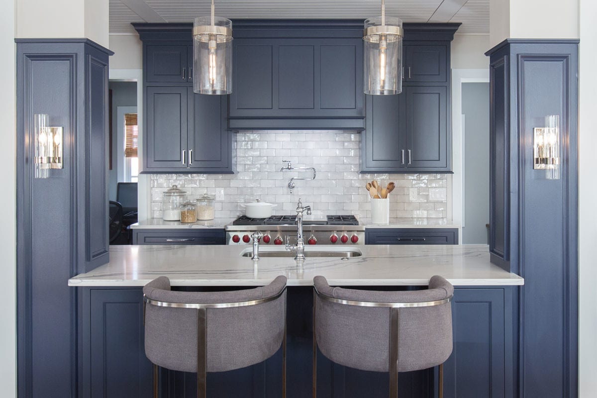 kitchen with indigo cabinetry and white backsplash and countertops