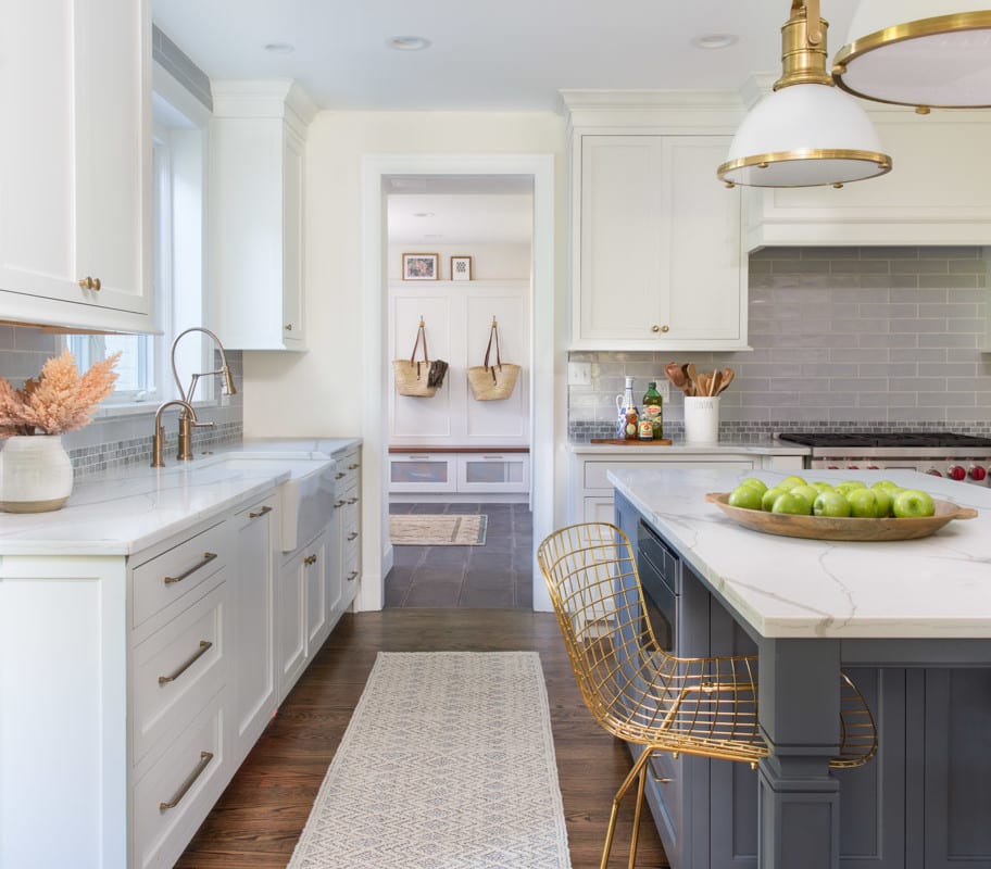 A primarily white-colored kitchen with dark wooden floors and hints of periwinkle and gold.
