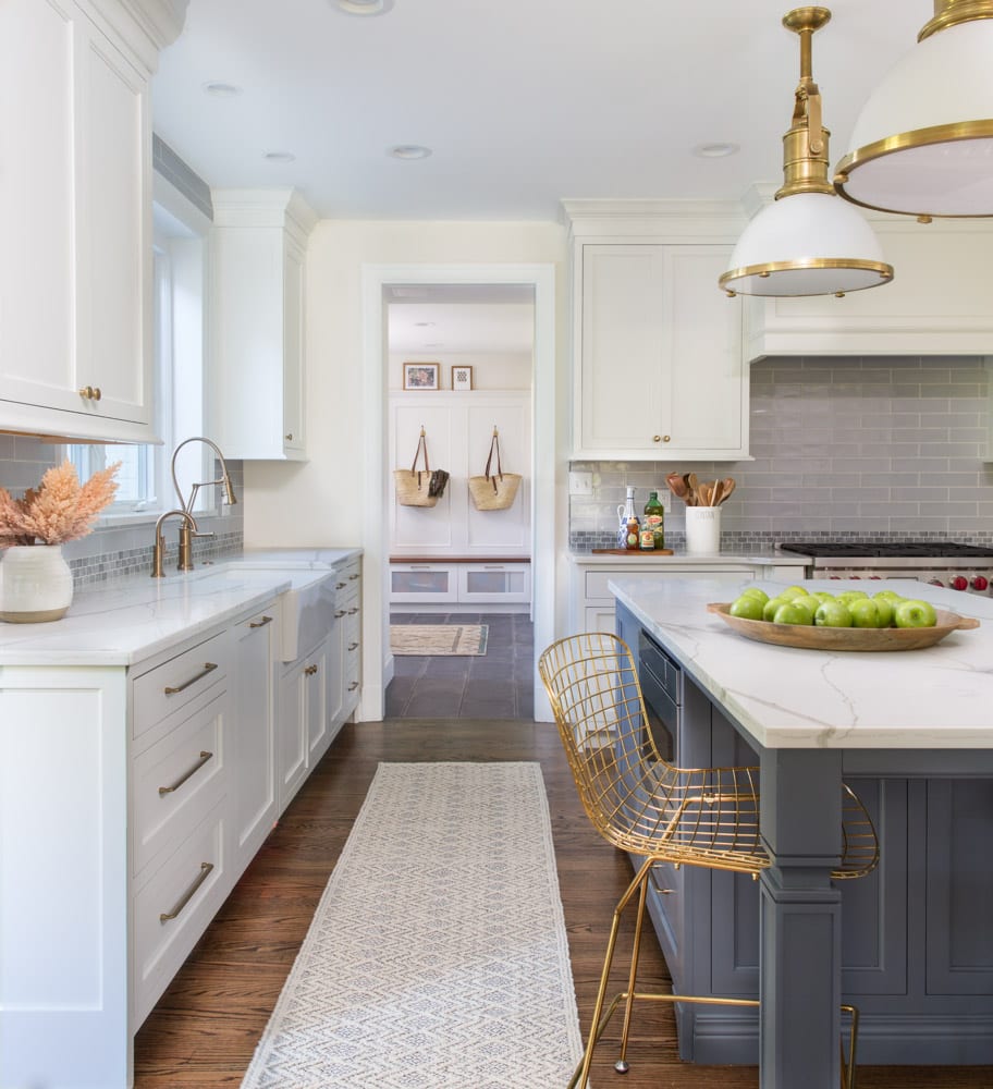 A primarily white-colored kitchen with dark wooden floors and hints of periwinkle and gold.