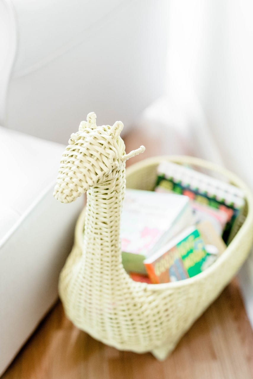 A giraffe-shaped wicker basket is the perfect place to store children's books, especially with natural light from windows next to it.