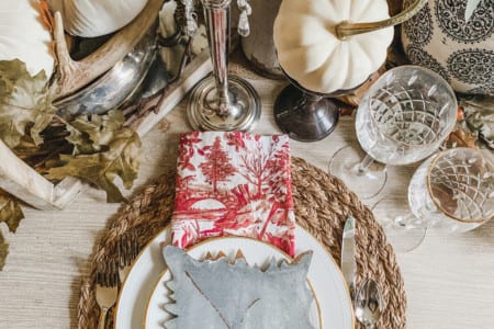 A large spread of thanksgiving decor with wicker placemats, white pumpkins, and other decorative items.