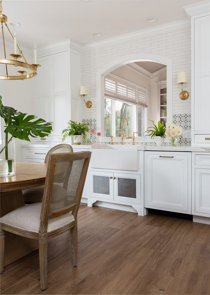 A cozy white and wood-filled kitchen with a large mirror and gold and green accents around the room.