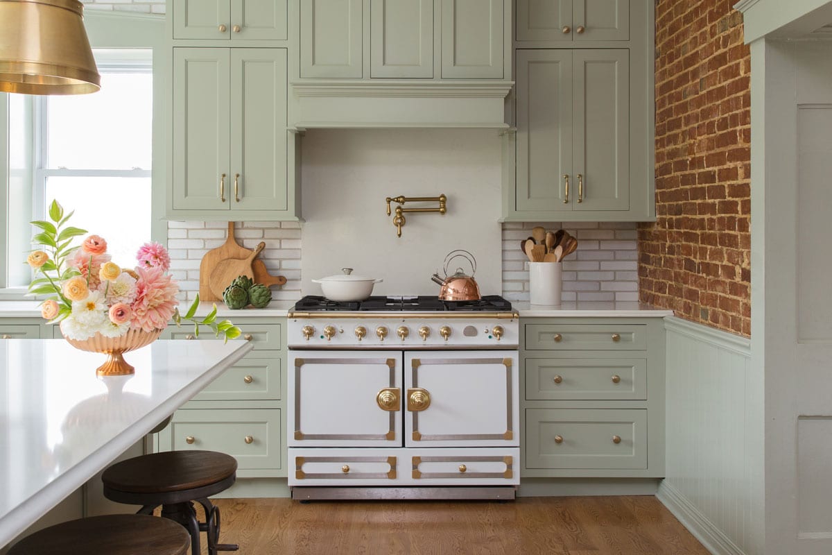 a spacious kitchen with brick walls and pastel green cabinetry