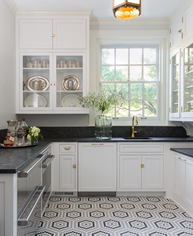 black and white kitchen with gold accents. large white window on far wall for natural light