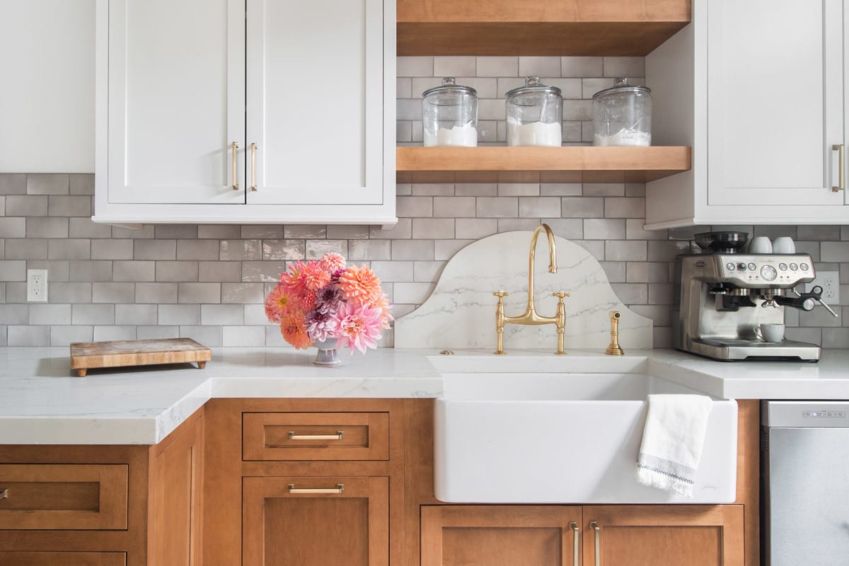 light brown and white kitchen remodel with coffee maker. sugar, flour, and creamer jars on brown shelf and orange pink flowers on counter.