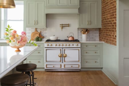 bright kitchen with light green cabinetry and gold fixtures