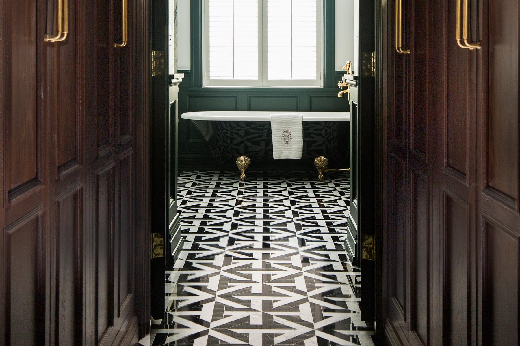a dramatic master bathroom with dark cabinetry and black and white geometric tile