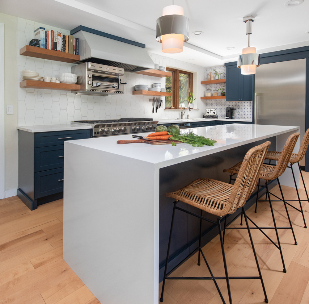 Gorgeous kitchen with navy cabinetry and grey countertops and wood floating shelves