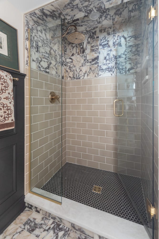eclectic walk-in shower with multiple styles of neutral tile and gold fixtures