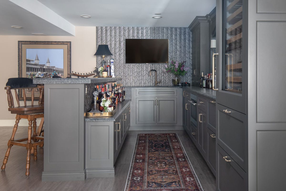 spacious wet bar with grey chevron wallpaper and grey cabinetry and countertops