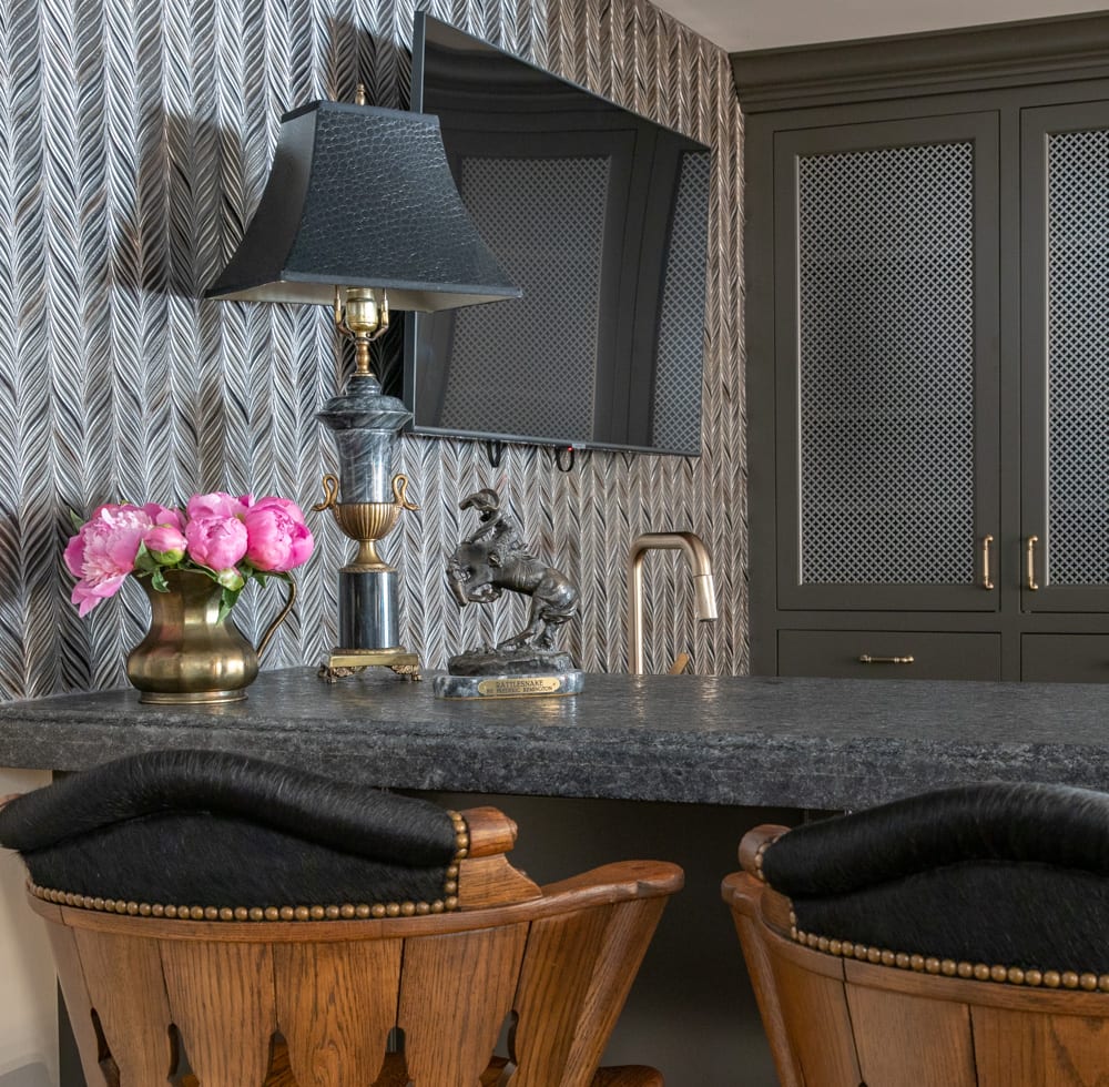 black and gold decor on grey granite countertops in a wet bar with grey chevron wallpaper