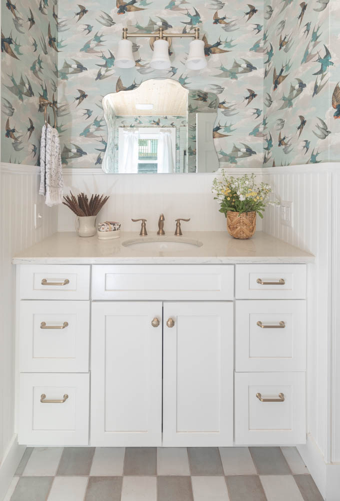vanity with white cabinetry and cream countertops in a coastal bathroom