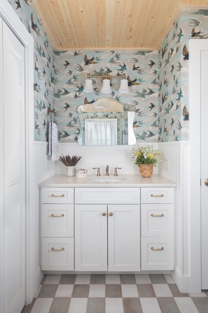 a white vanity in a coastal bathroom with bird wallpaper