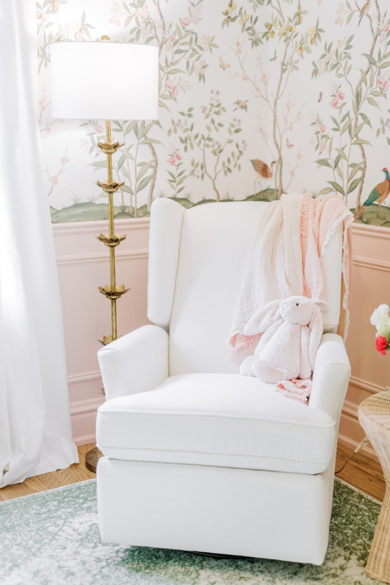 a white rocking chair in the corner of a floral and pastel nursery