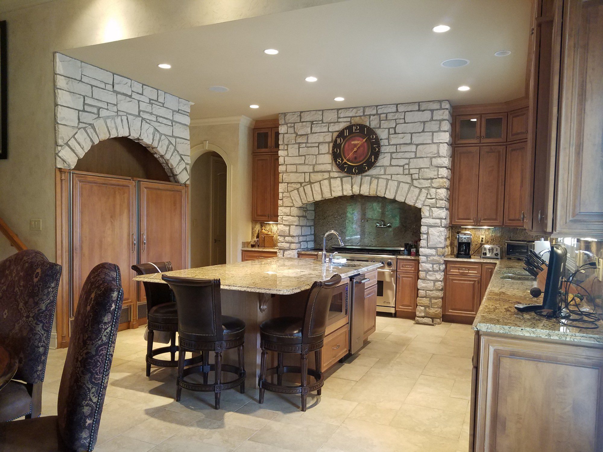 large tuscan style kitchen with stone archways and a beige color scheme