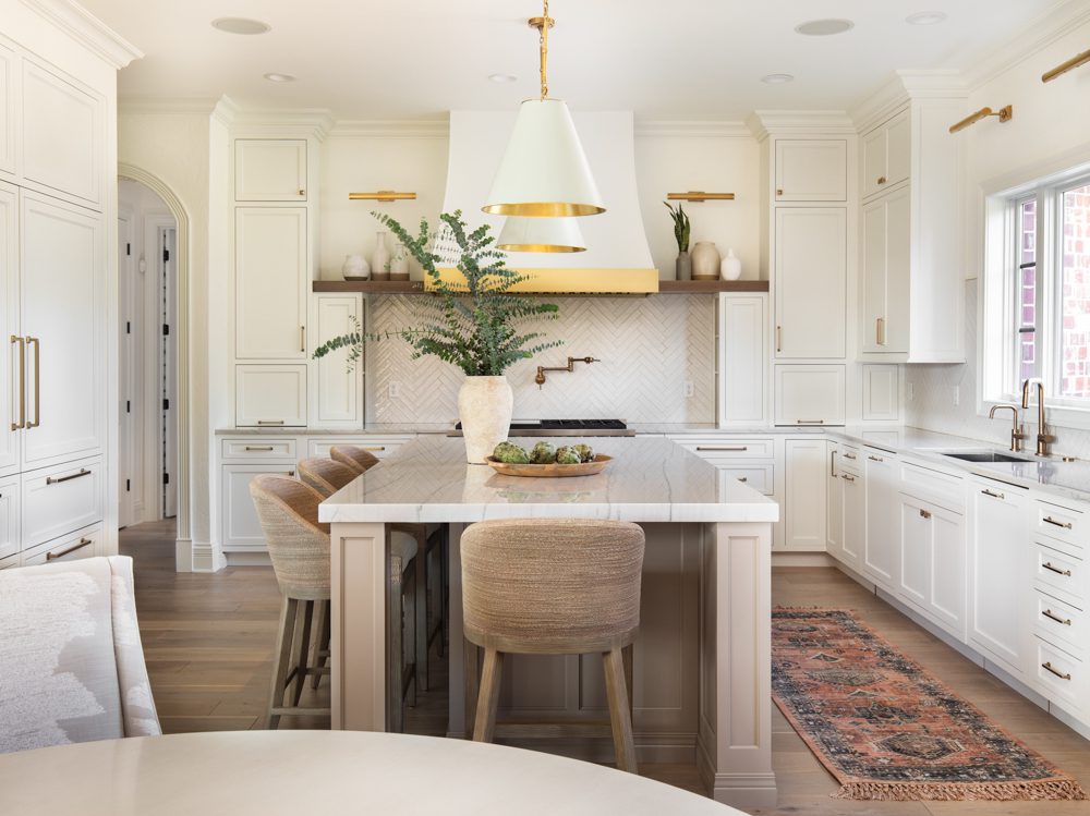 large kitchen island with marble countertops and beige cabinetry in a spacious bright kitchen