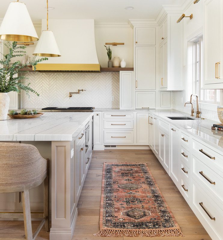 spacious walkway in large kitchen with white elements and gold accents