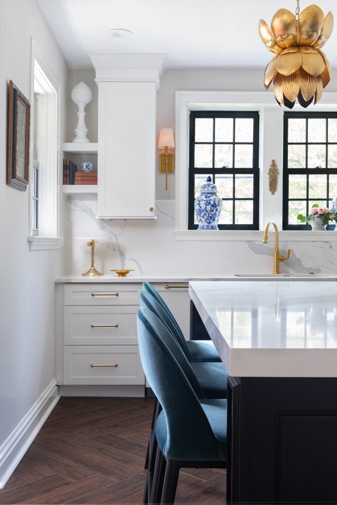 bright kitchen with marble backsplash and countertops and navy and gold accents