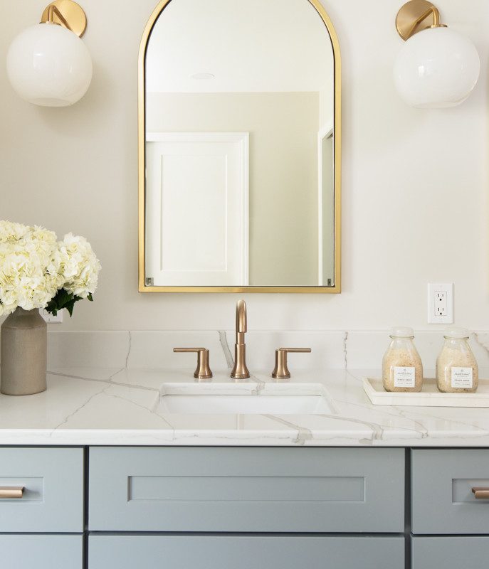 simple vanity with light blue cabinetry and gold accents