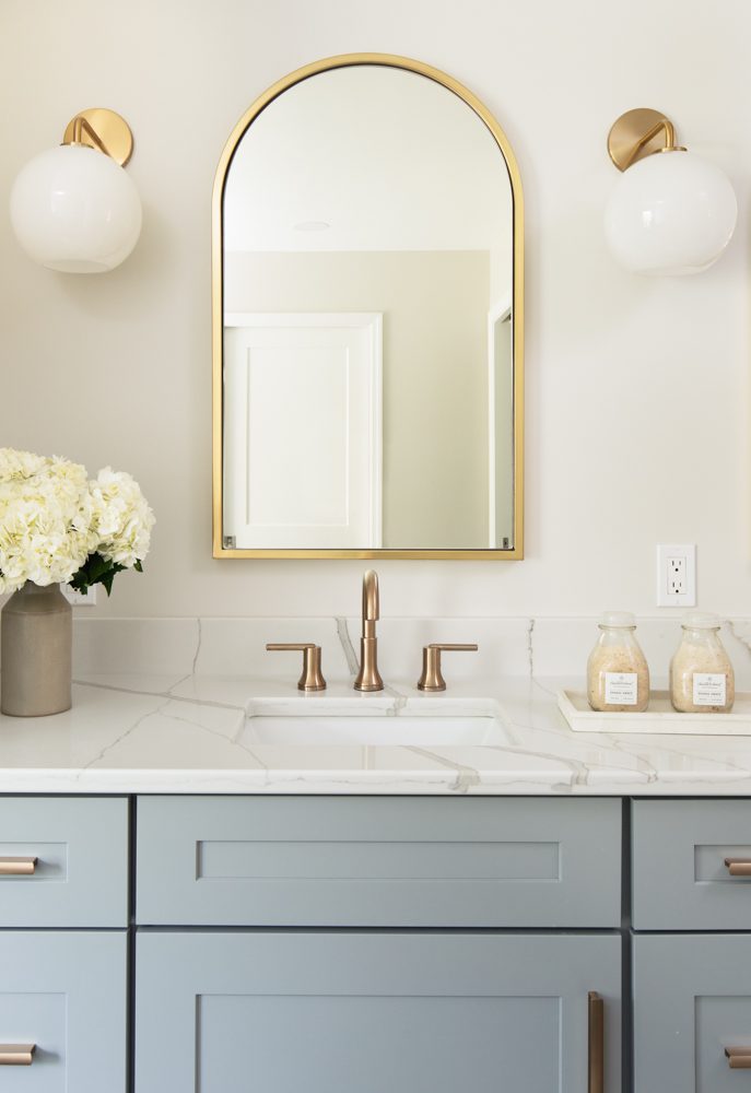simple vanity with light blue cabinetry and gold accents