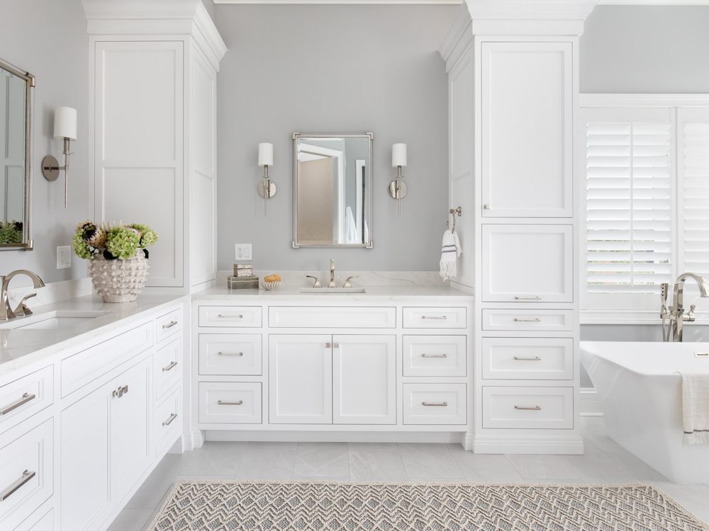 a large bright white master bathroom with silver accents and hardware