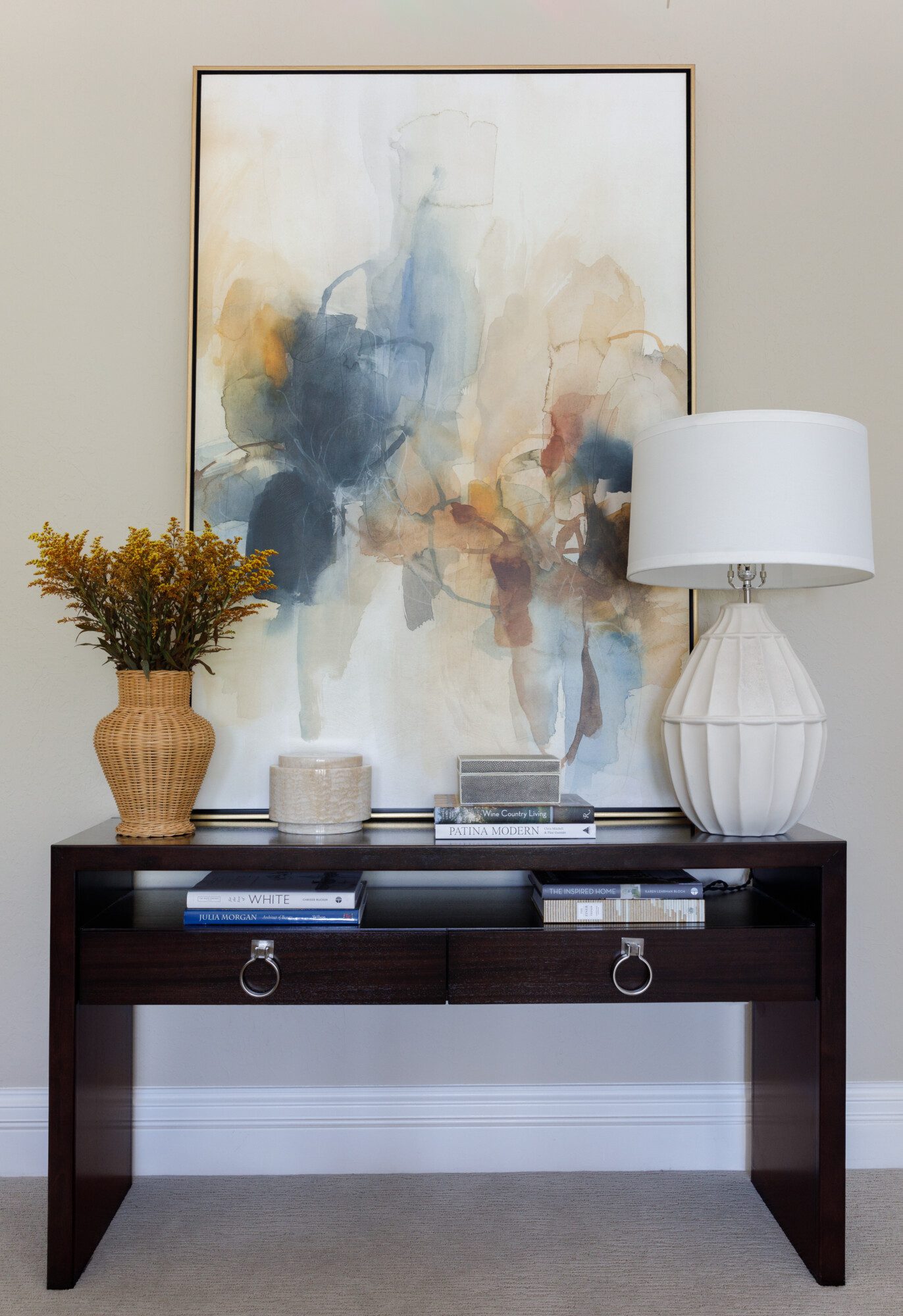 Dark wood console table with decor and a large painted canvas.