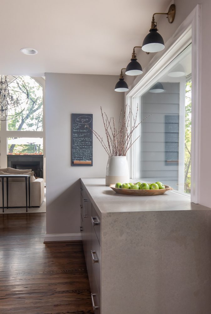 light peering through a large window into a grey kitchen