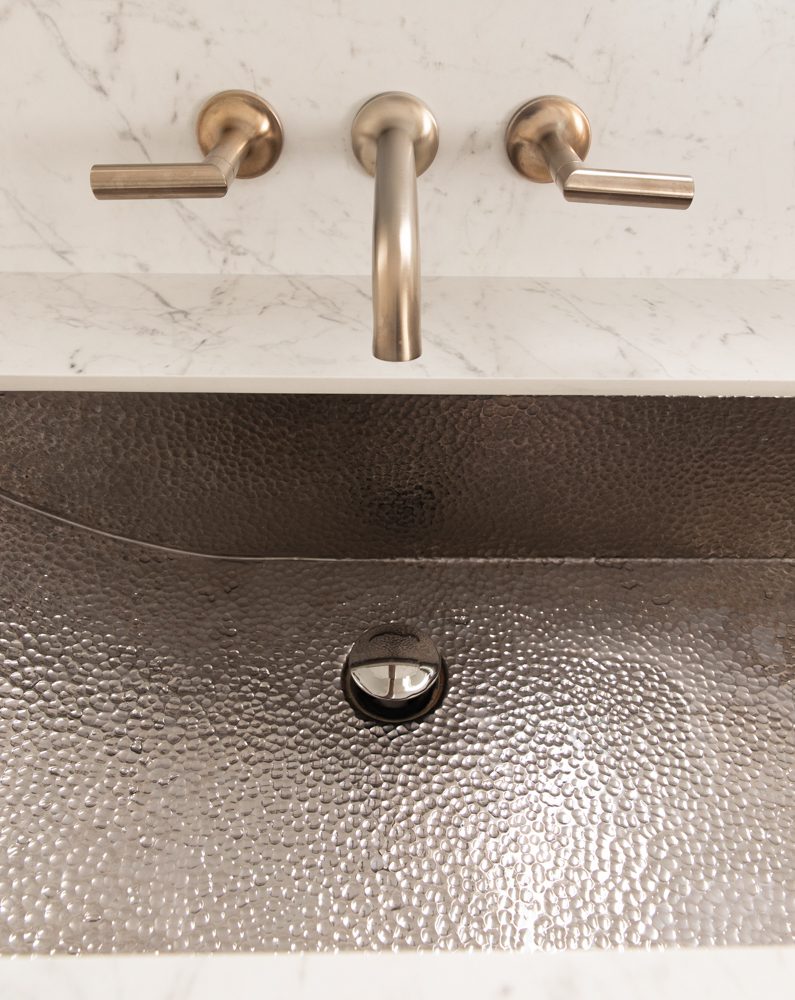 textured grey sink with marble countertops and gold brass hardware