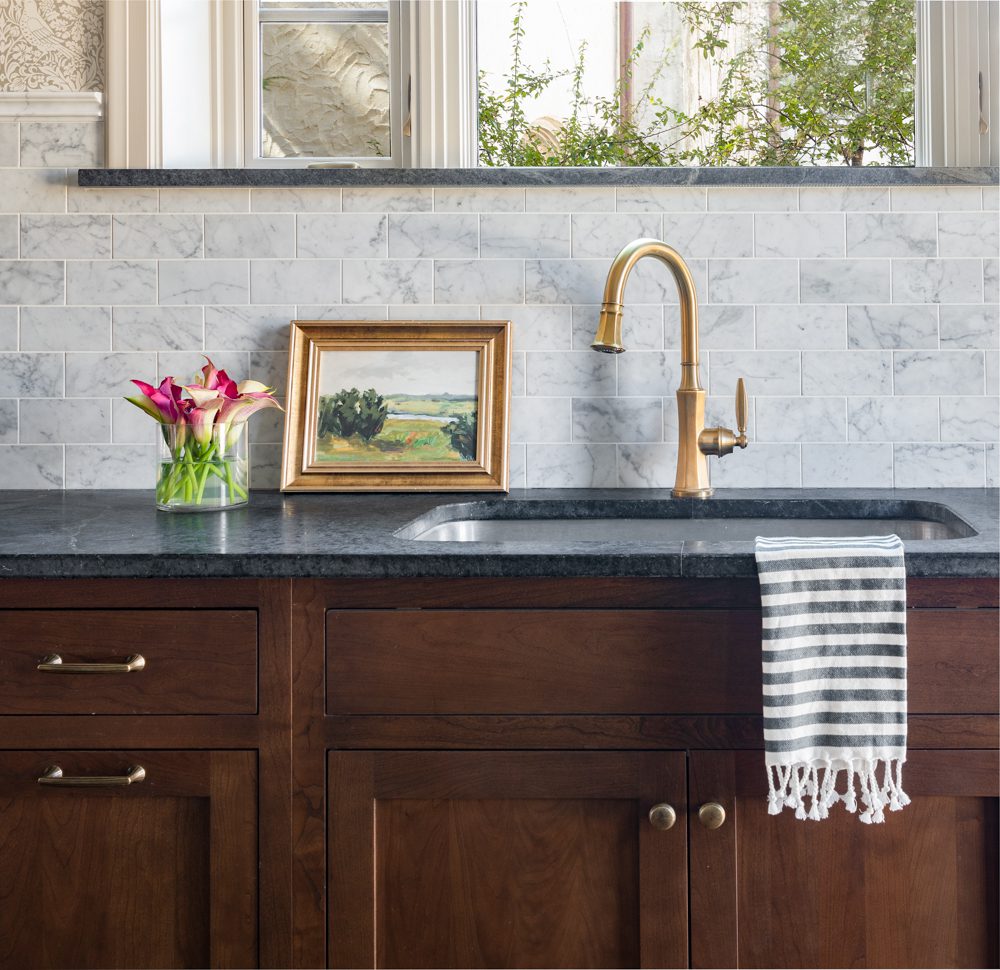 large sink with a gold faucet on dark grey countertops