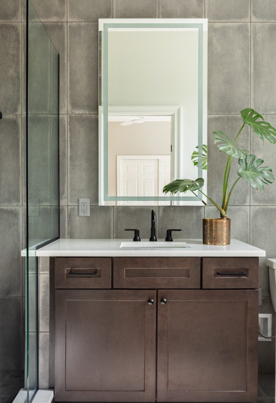 brown vanity in a bathroom with grey tiled walls