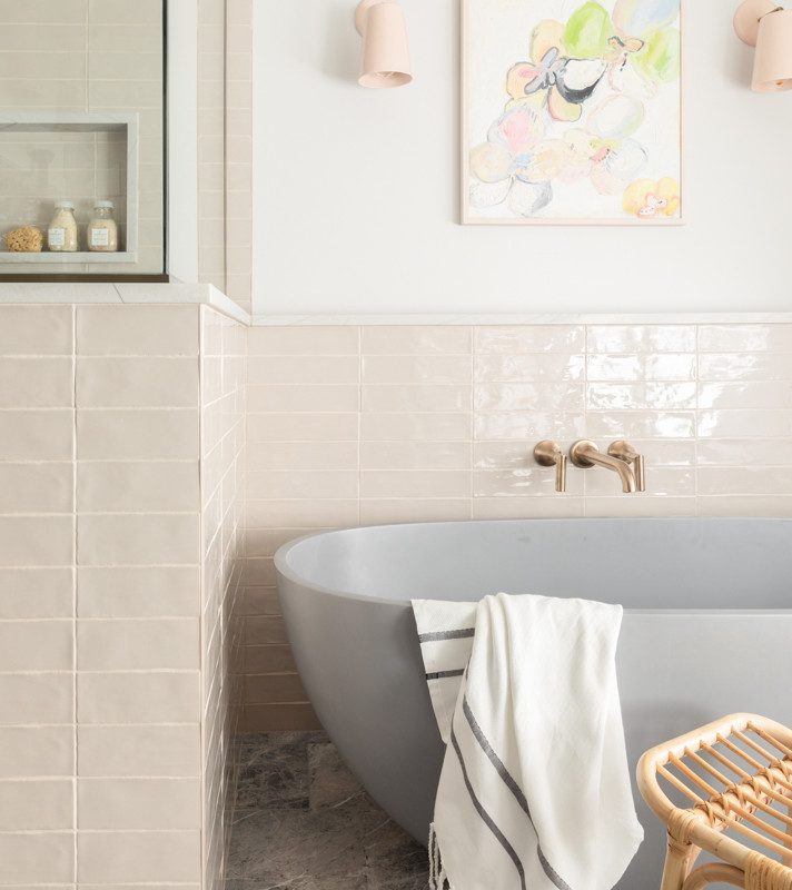 a grey bathtub with surrounding pink tile and gold accents