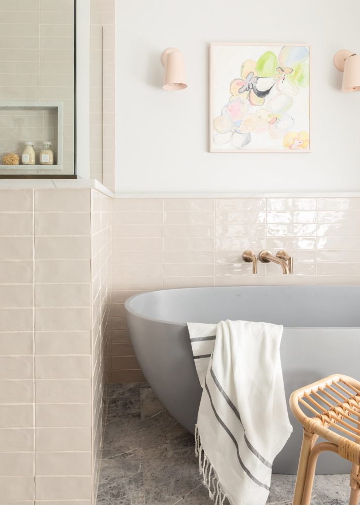 a grey bathtub with surrounding pink tile and gold accents