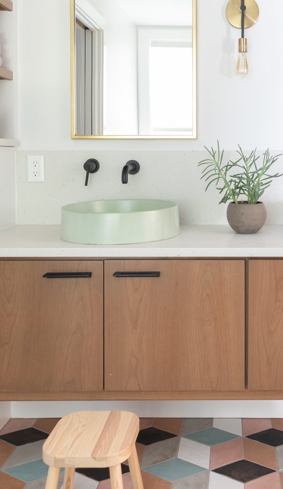 a vanity with a light green sink and wood cabinetry
