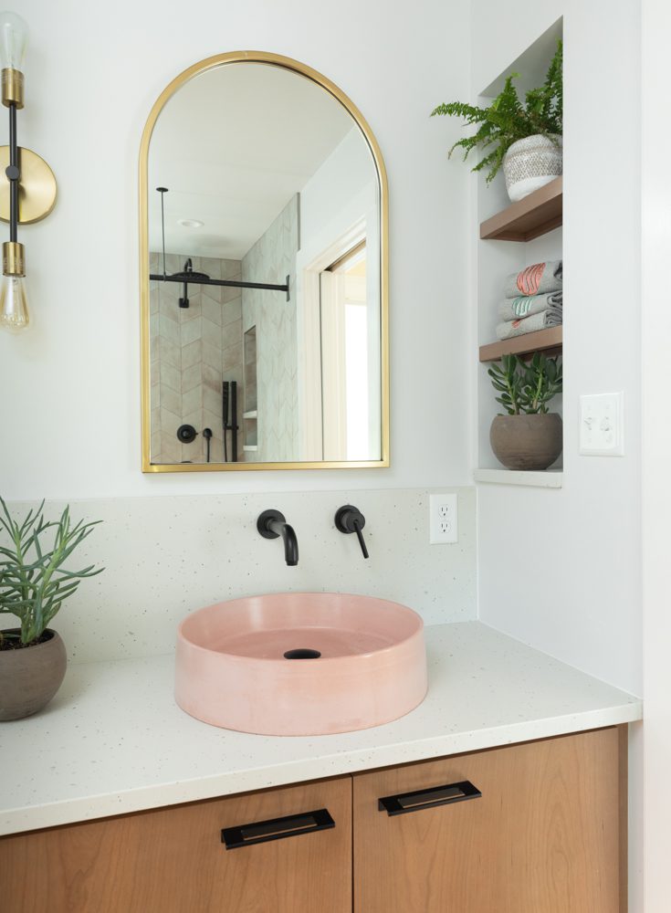 a vanity with a pink sink and black accents