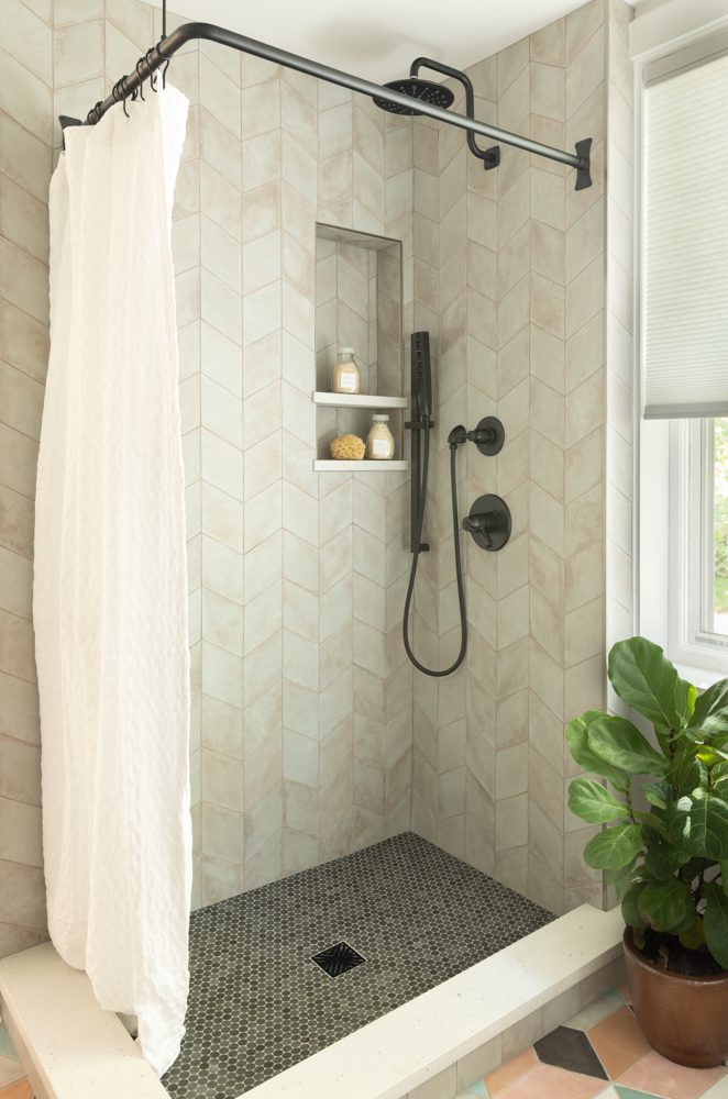 a light and airy shower with black chrome accents and cream colored tiles