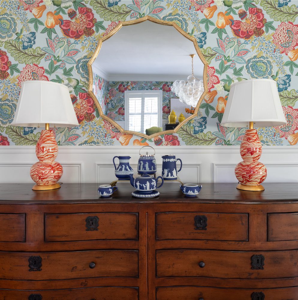 a dresser with colorful decor against floral wallpaper