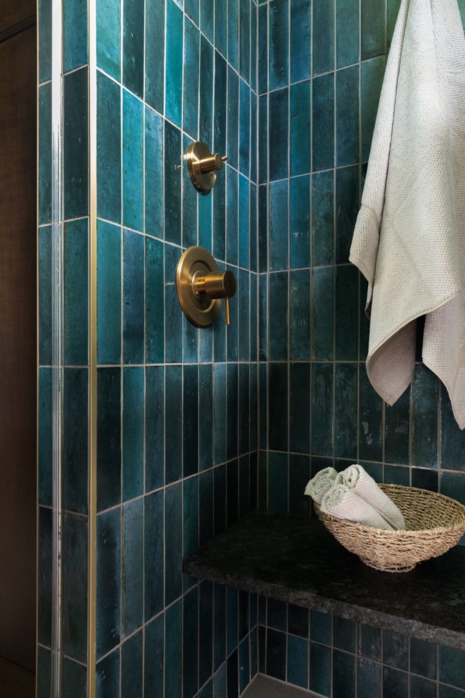 shower with blue green tiles and gold accents