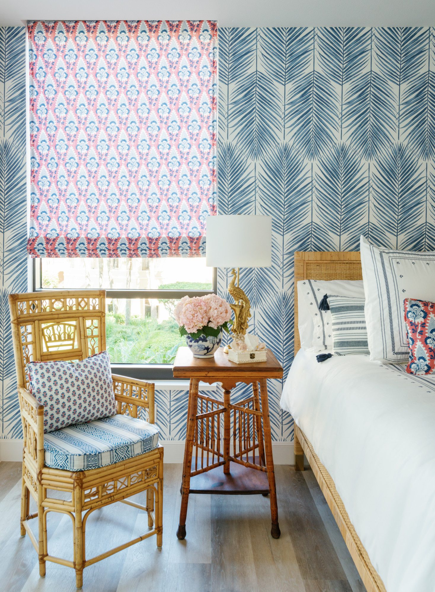 the corner of a bedroom with a big window and blue wallpaper