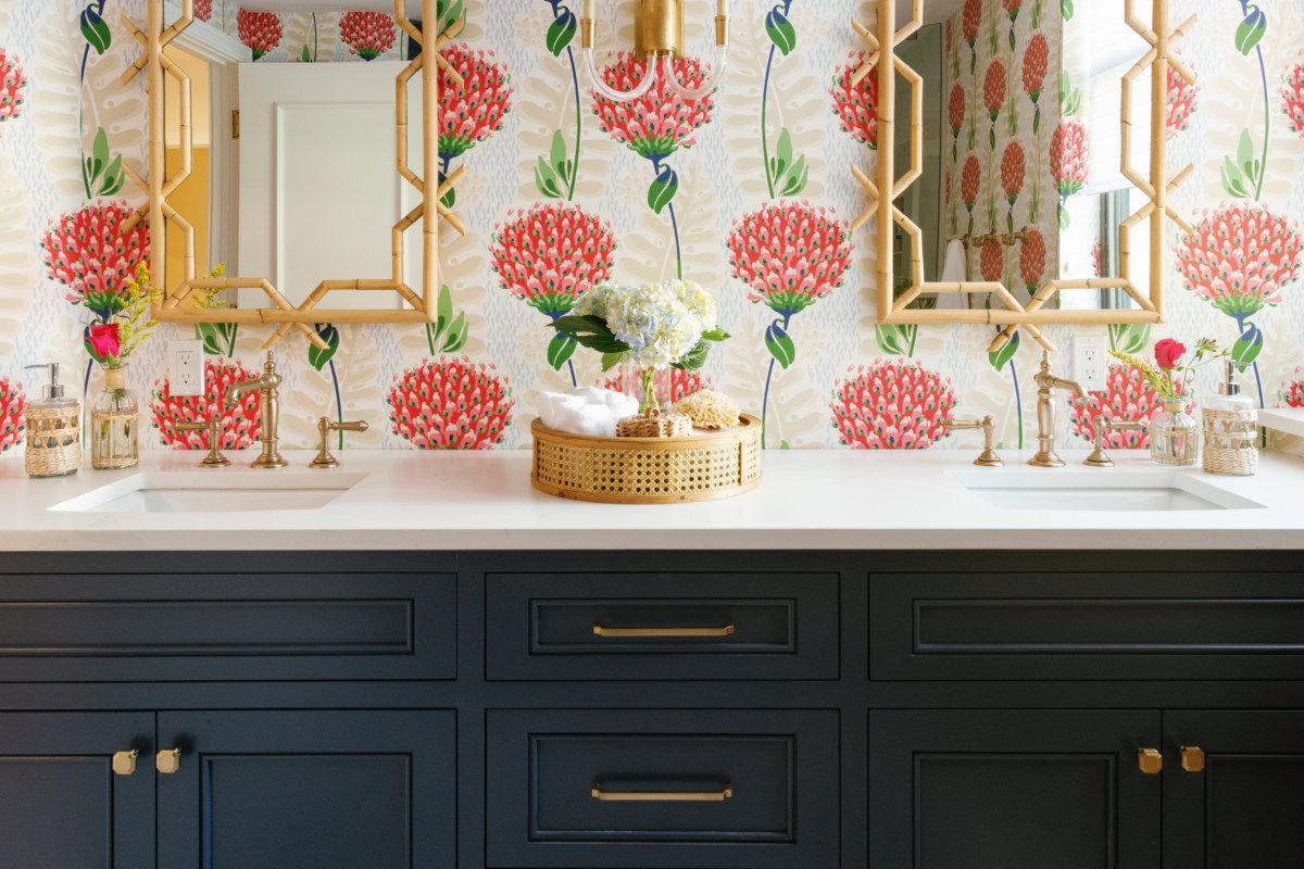 a double vanity with floral wallpaper and natural accents