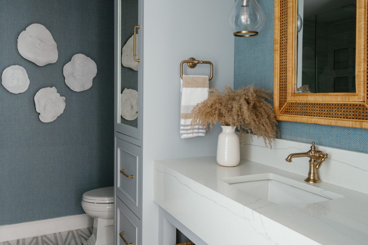 a spacious light blue bathroom with gold and natural accents