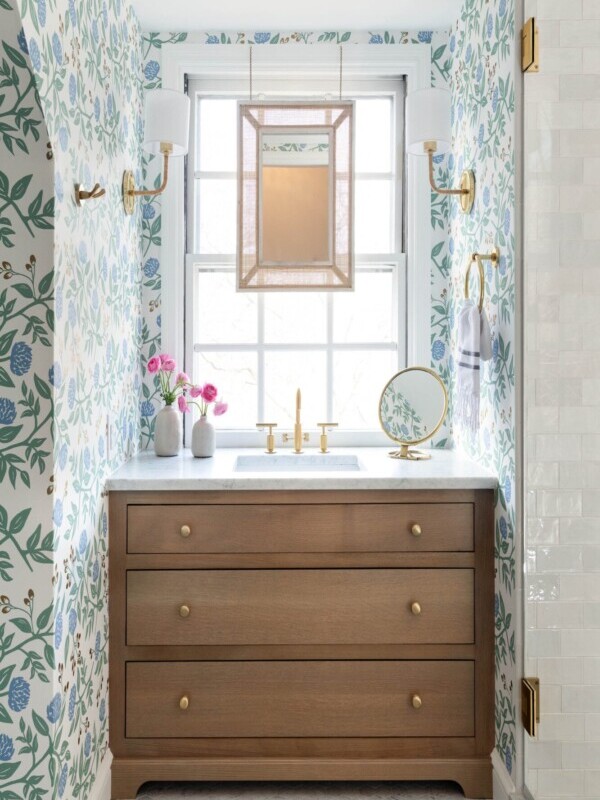 Beautiful bathroom sink with blue and green patterned wallpaper and gold accents