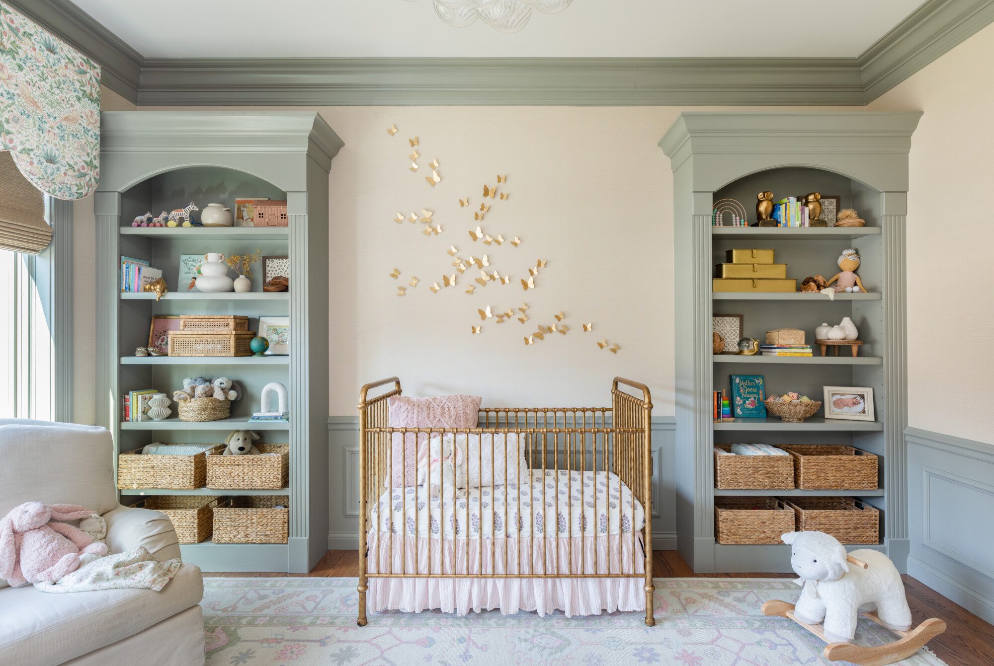 a crib in between 2 seafoam green shelves full of toys and books