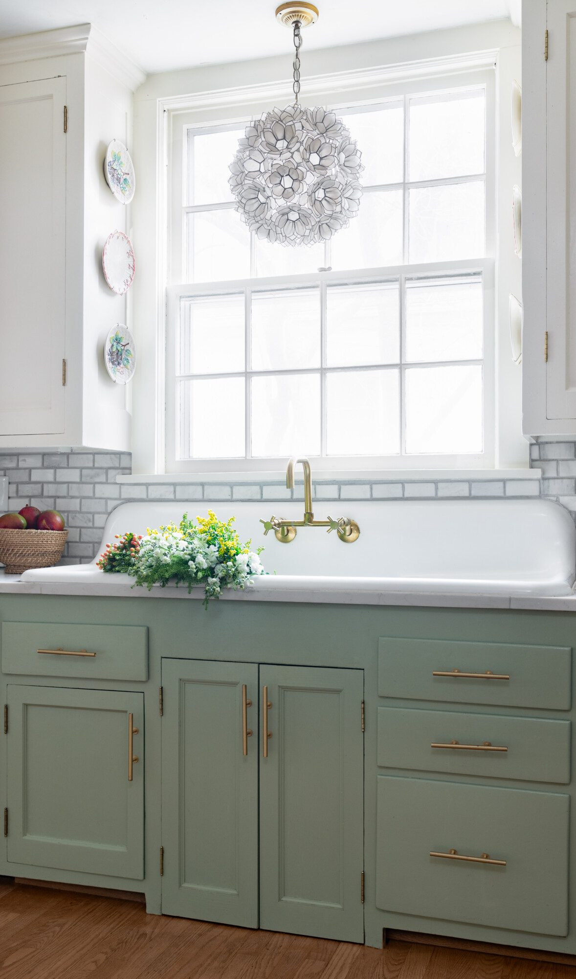 a sage green farmhouse sink looks out a window.