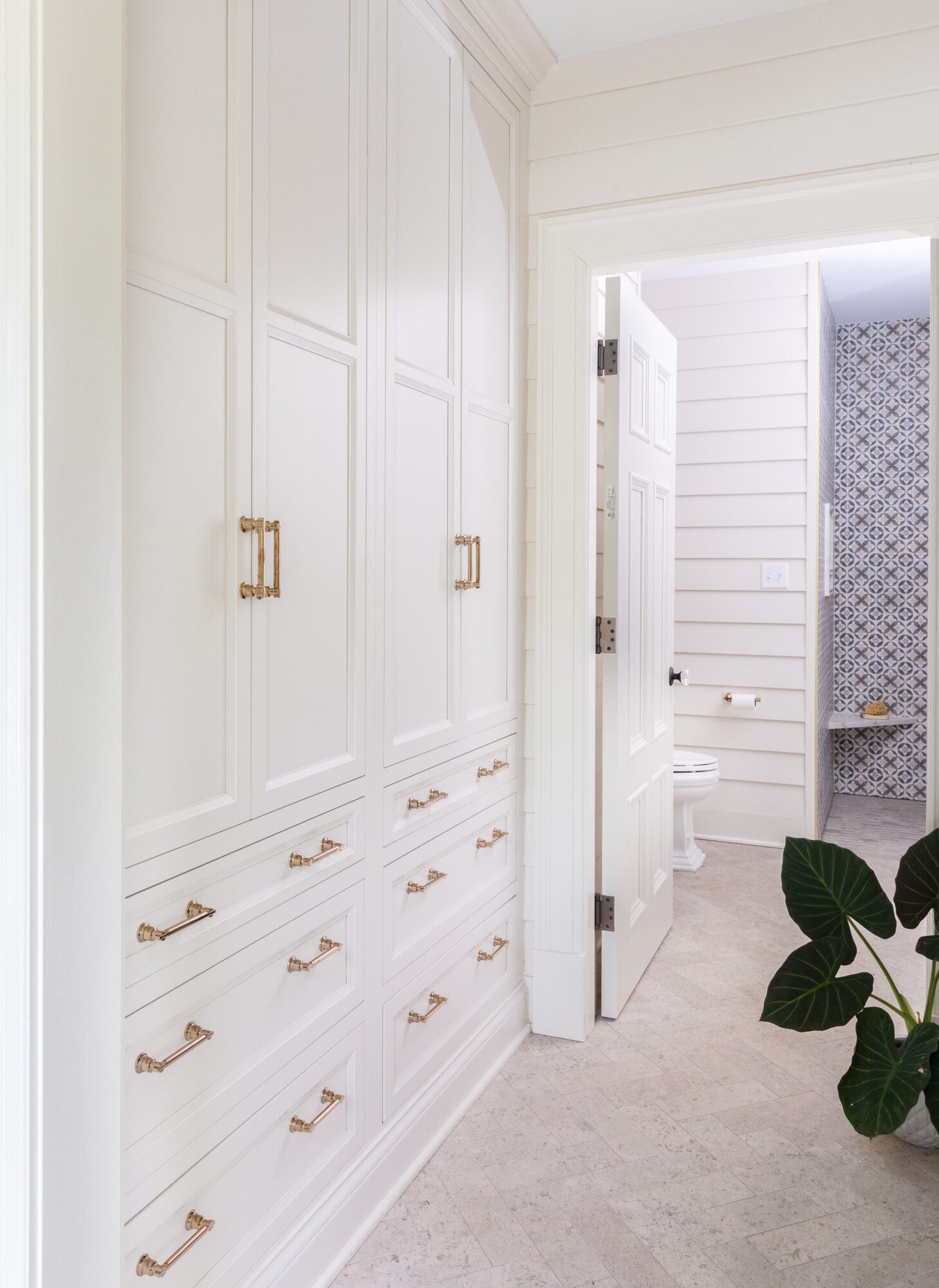 All white floor to ceiling storage closets and drawers with gold accents